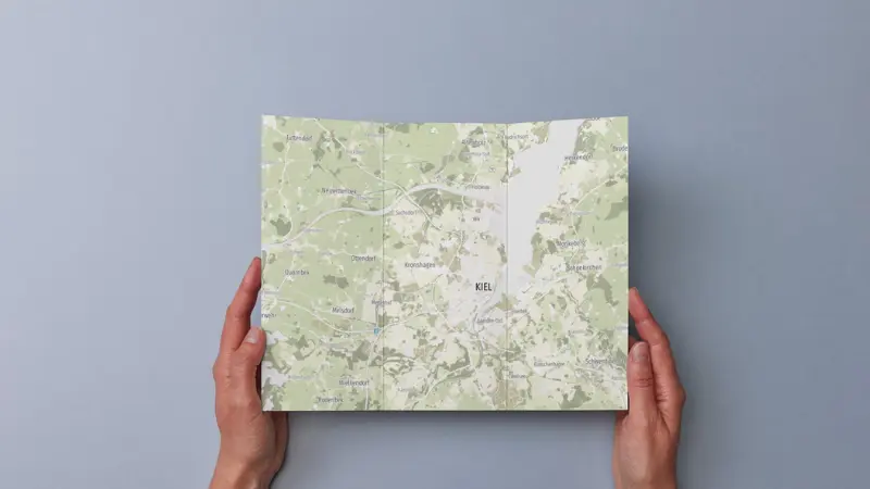 Aufgeschlagene Broschüre mit topographischer Karte wird von zwei Händen gehalten